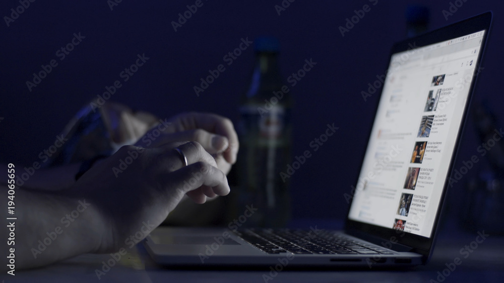 Poster A man's hands working on the laptop at night. The laptop is on the table. View from the top. Close-up shot. Close-up Of A Person's Hand Typing On Laptop. typing in notebook computer. Crime concept