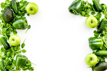 Green vegetables background. Shiny bell pepper, cucumber, arugula salad, avocado and fresh apple on white background top view copy space