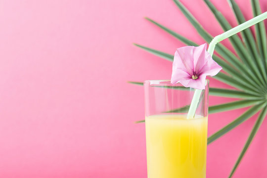 Tall Glass with Freshly Squeezed Pineapple Citrus Tropical Fruit Juice with Straw and Flower. Cherry Pink Background Palm Tree Leaf Sunlight. Summer Vacation Traveling Vitamins Detox Concept