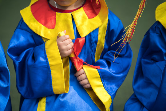 Preschool Kid Wearing Graduation Dress And Holding Diploma Closeup