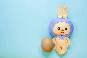Easter rabbittoy with one brown egg is on blue background.