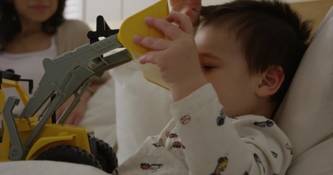 Toddler boy brings toy backhoe to bed for afternoon nap - super cute - slow motion