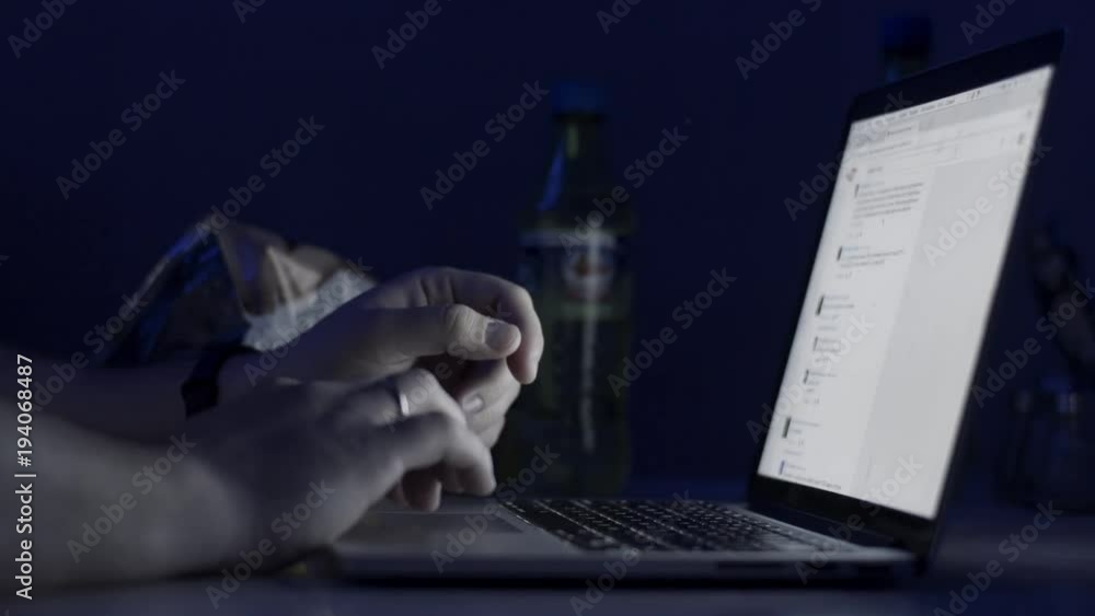 Poster a man's hands working on the laptop at night. the laptop is on the table. view from the top. close-u