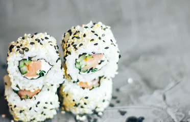 Japanese sushi roll philadelphia on black stone. Selective focus. Blurred foreground and background. Concrete grey background