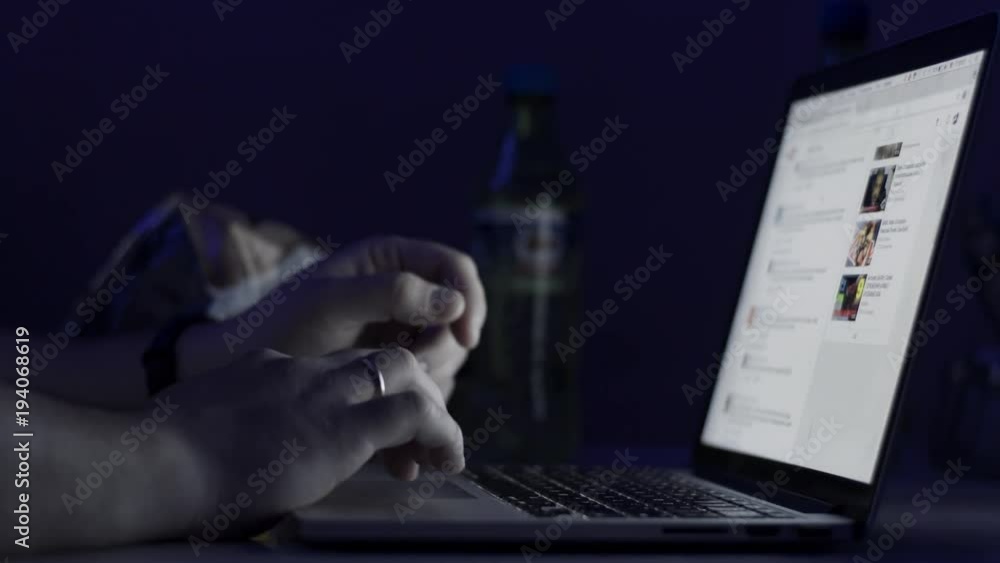 Poster a man's hands working on the laptop at night. the laptop is on the table. view from the top. close-u