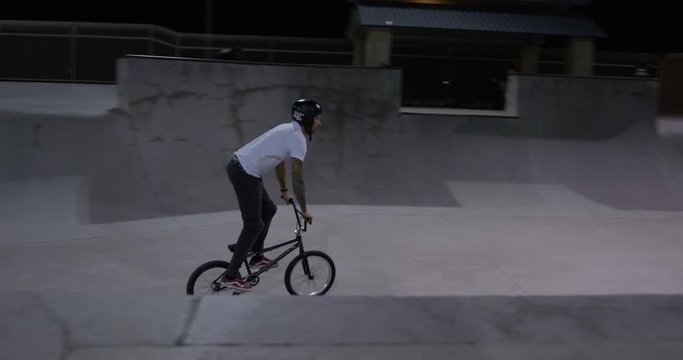 BMX rider rides through skatepark at night