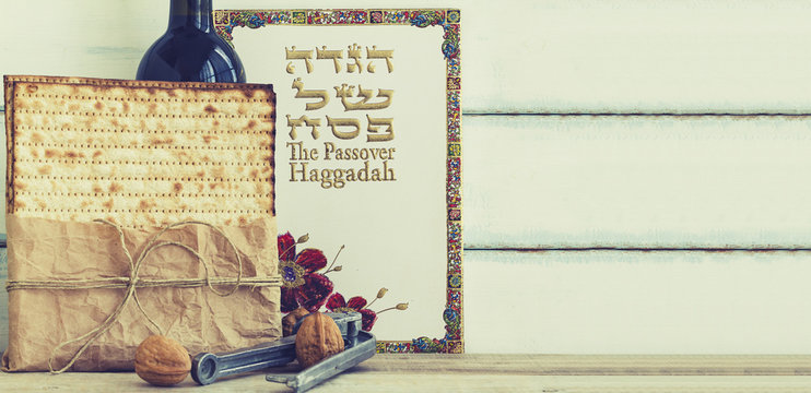 Pack of matzah or matza, Passover Haggadah and Kosher red wine on a vintage wood background. Jewish Passover holiday composition with copy space.Hebrew text translation: The story of Passover