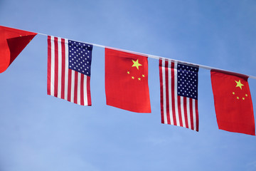 USA and China flags hanging under blue sky