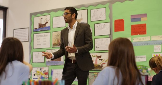 4K Elementary school children listening attentively to the teacher in classroom. Slow motion