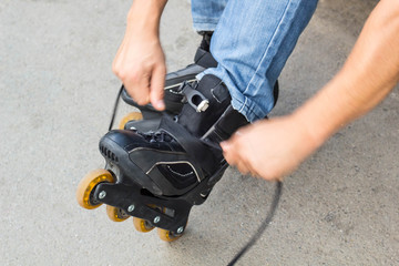 Closeup of man guy putting on roller skates outdoor