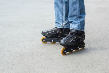 Young man in blue jeans riding roller skates in the city. Close up legs