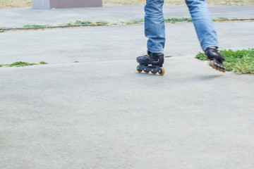 Young man in blue jeans riding roller skates in the city. Close up legs
