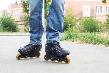 Young man in blue jeans riding roller skates in the city. Close up legs