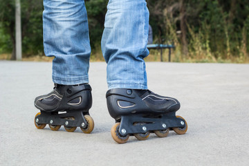 Young man in blue jeans riding roller skates in the city. Close up legs