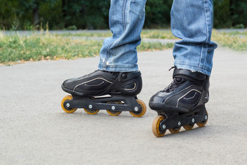 Young man in blue jeans riding roller skates in the city. Close up legs