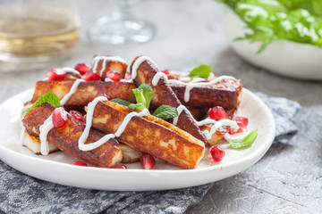 Crispy Halloumi cheese sticks Fries with yogurt sauce, pomegranate seeds and mint
