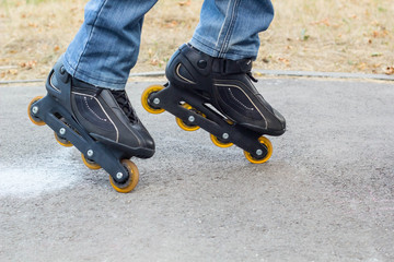 Young man in blue jeans riding roller skates in the city. Close up legs