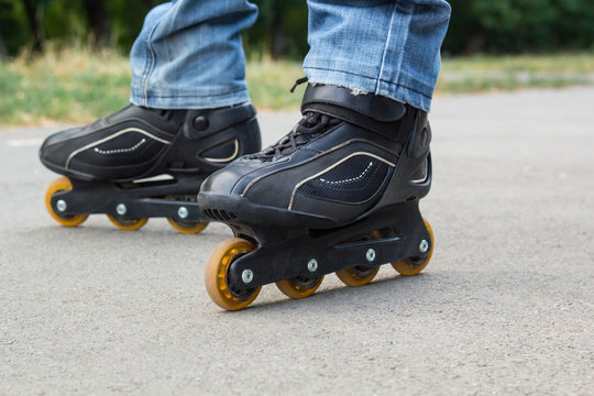 Young man in blue jeans riding roller skates in the city. Close up legs