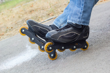 Sport skating in park. Guy putting on roller skates. Man in outdoor fitness activities
