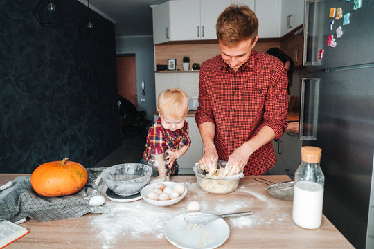 Dad and son make dough in the kitchen