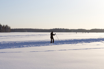Person skiing on the lake ice in Finland. Sunset and glowing snow.