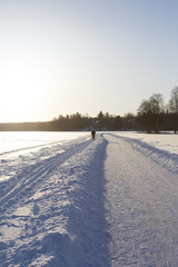 Fototapeta na wymiar Person skiing on the lake ice in Finland. Sunset and glowing snow.