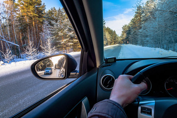 Driving SUV car in winter on forest road with much snow. rearview mirror. the car goes to overtake. auto makes overtaking.road view from inside the car