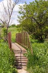 small iron bridge with old iron wheel in the countryside