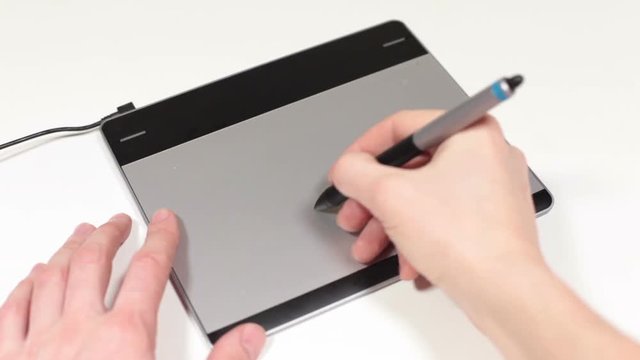 Small digitized pad and human hands with pen drawing and  designing, white background, close up view