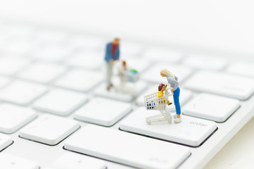 Miniature person: a shopper pushes a shopping cart on a shift button on white keyboard. Concept retail business increased competition from internet online e-commerce.