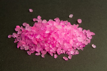 Bath salt. Pink crystals of salt on a dark background