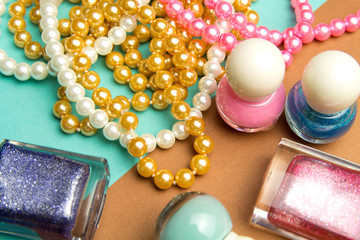 Nail Polish and pearl beads on turquoise and brown geometric background. Color trend, fashion pattern.