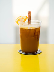 One glass of cold coffee mix with orange juice and soda , cinnamon, white background , selective focus