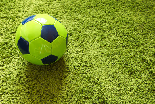 Football (Soccer) ball on a green surface imitating artificial grass. Sports photography 