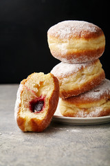 A stack of three sufganiyot donuts with jelly on black background