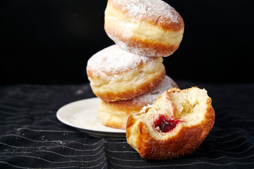 A stack of three sufganiyot donuts with jelly on black background