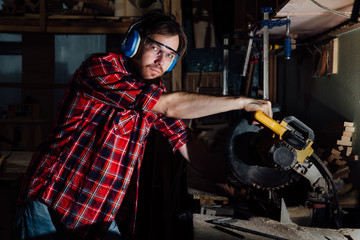 Fototapeta na wymiar brunette man profession carpenter builder saws with a circular saw a wooden board.