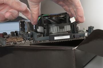 Close up of man hands installing CPU cooler fan on new, modern  motherboard