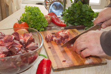 Cook hands with raw meat and vegetables in kitchen