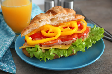 Plate with delicious croissant sandwich on table