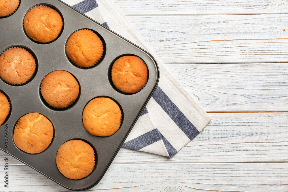 Wall mural Baking tray with tasty cupcakes on table. Fresh from oven