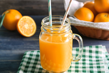 Mason jar with fresh orange juice and fruit on dark wooden table
