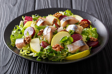 Gourmet salad with mackerel with apples, walnut, beetroot and mix lettuce close-up on a black plate. horizontal
