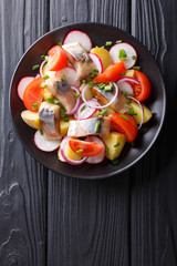 Delicious salad of smoked mackerel with potatoes, radish and tomatoes close-up. Vertical top view