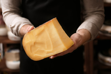 Young worker holding cheese in shop