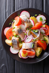 Salad of vegetables with smoked mackerel close-up on a plate. Vertical top view
