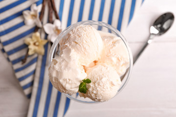 Glass with delicious vanilla ice cream on table