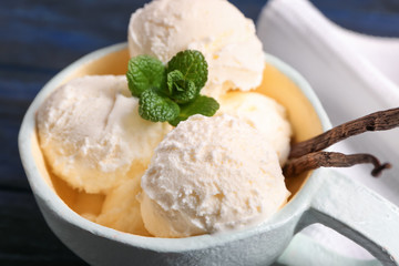 Cup with delicious vanilla ice cream on table, closeup