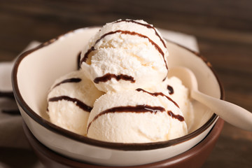 Bowl with delicious vanilla ice cream on table, closeup