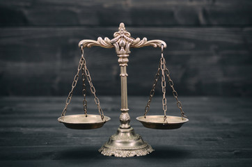  Scales of Justice on a black wooden background.